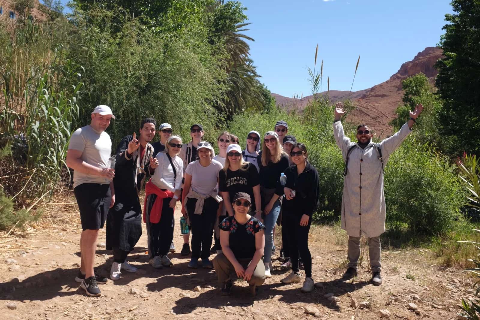 Travellers and a guide together on a path between gardens and rocky hills