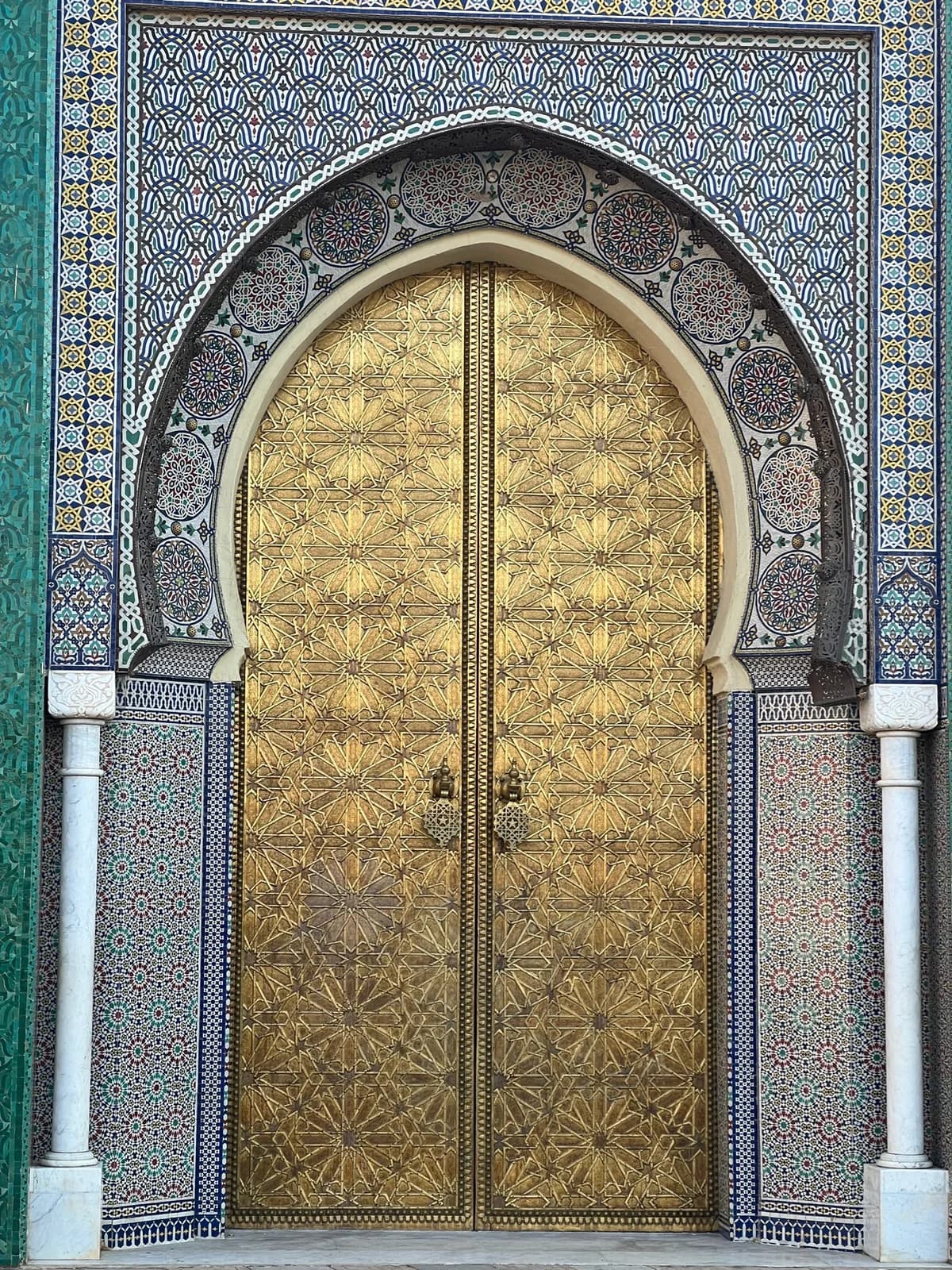 Intricate Moroccan tilework and a gilded ornamental doorway