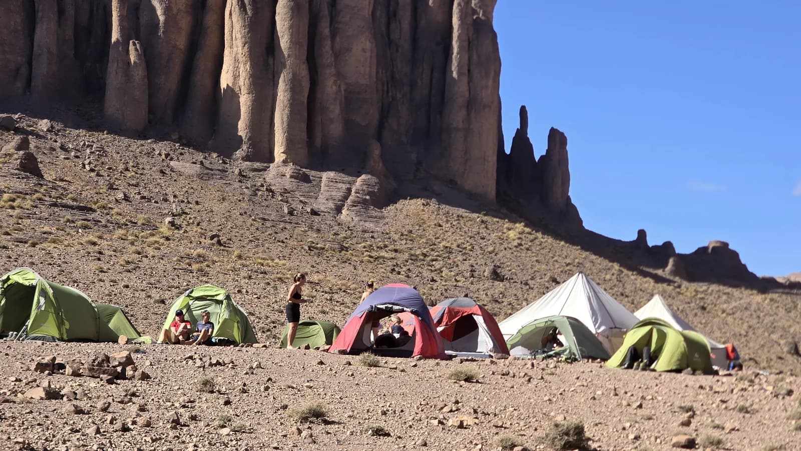 Small trekking tents pitched beneath tall rock formations
