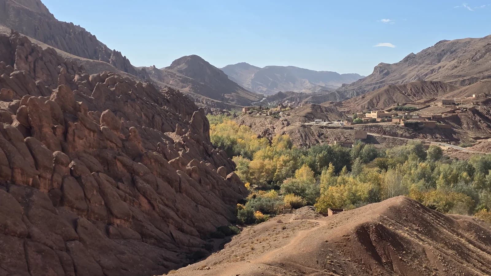 Rock formations above green gardens and a mountain valley