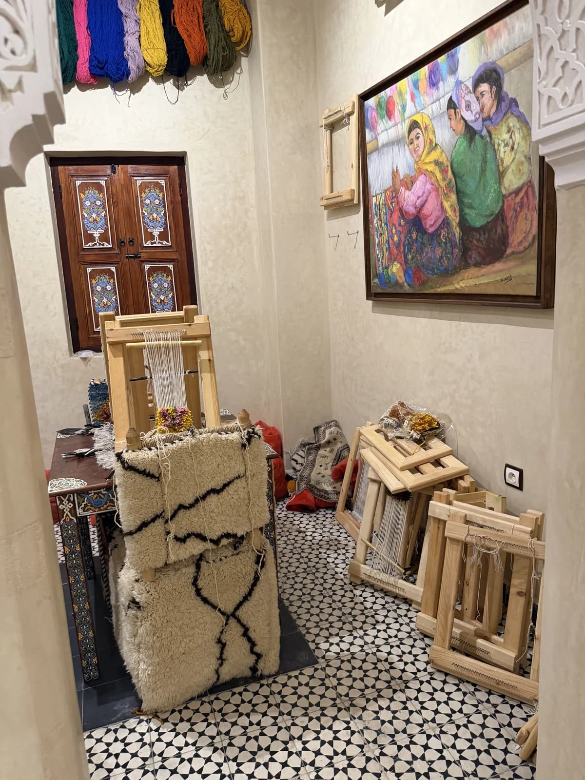 A woven carpet beside wooden weaving looms in a Marrakech textile display