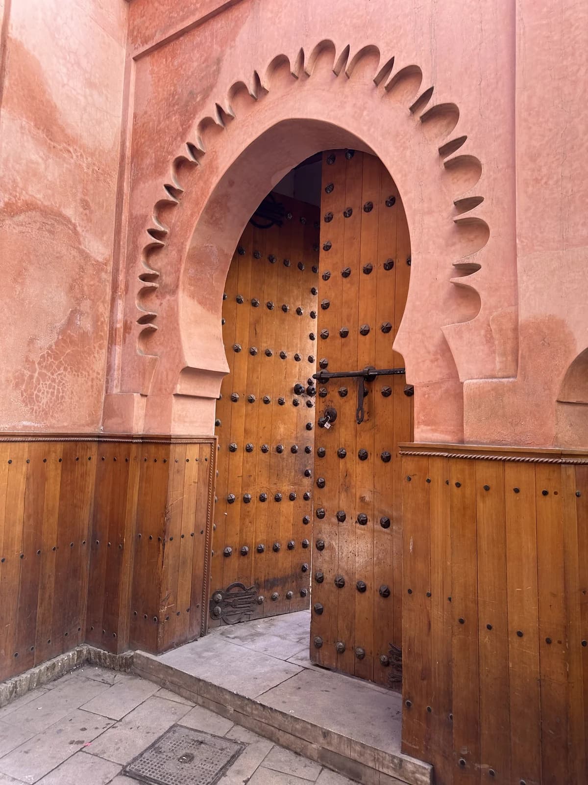 A wooden door framed by a pink scalloped arch in Marrakech